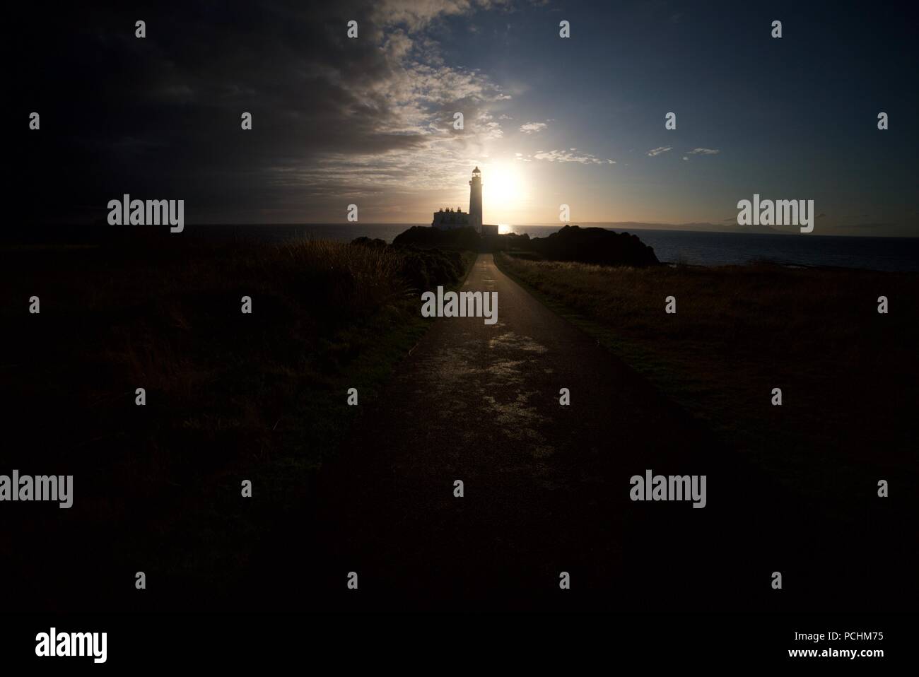 Silhouette di un faro (Turnberry Faro) lungo la costa dell'Ayrshire accanto al Trump Turnberry Golf, con il tramonto in background. Foto Stock