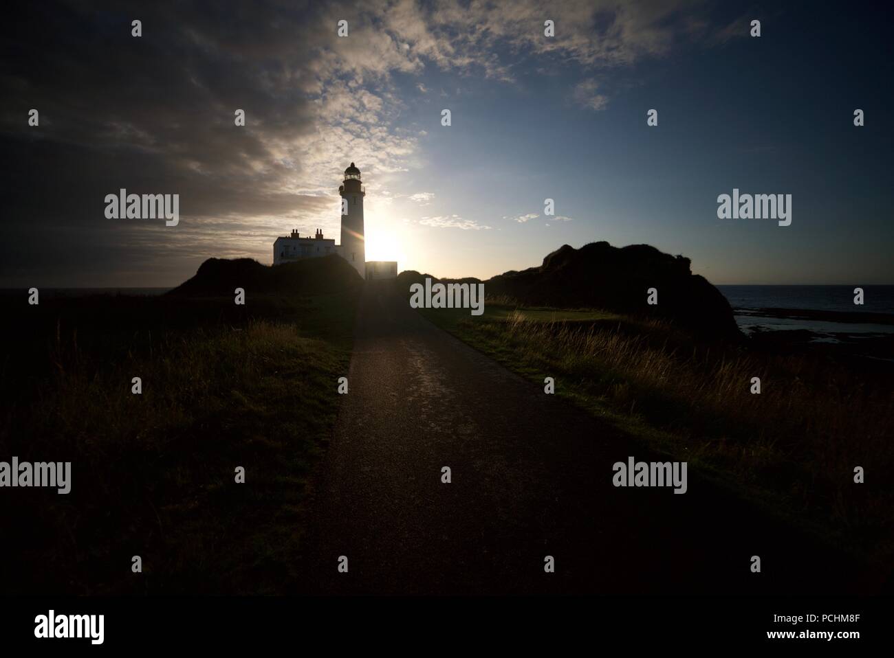 Il sole che splende dietro un faro (Turnberry Faro) presso la costa dell'Ayrshire accanto al Trump Turnberry Golf Course. Sole brillante dietro un faro. Foto Stock