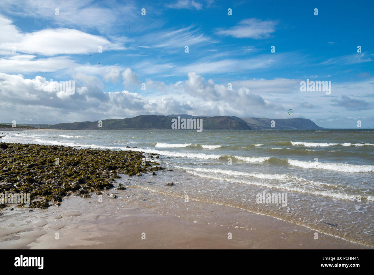 La sponda occidentale spiaggia di Llandudno, il Galles del Nord. Una soleggiata giornata di primavera guardando attraverso il mare di colline e montagne. Foto Stock