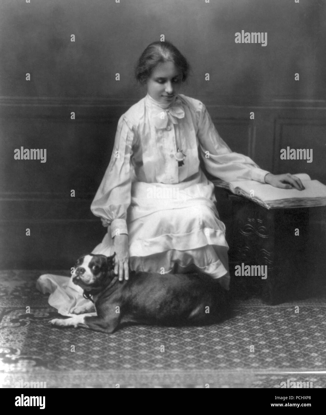 Helen Keller, ritratto seduto sul pavimento tenendo un bulldog francese cercando di destra nel 1902. Helen Keller (Giugno 27, 1880 - Giugno 1, 1968) era un autore americano, attivista politico, e docente. Lei è stato il primo sordo-persona cieca per guadagnare un bachelor del grado di arti. Foto Stock