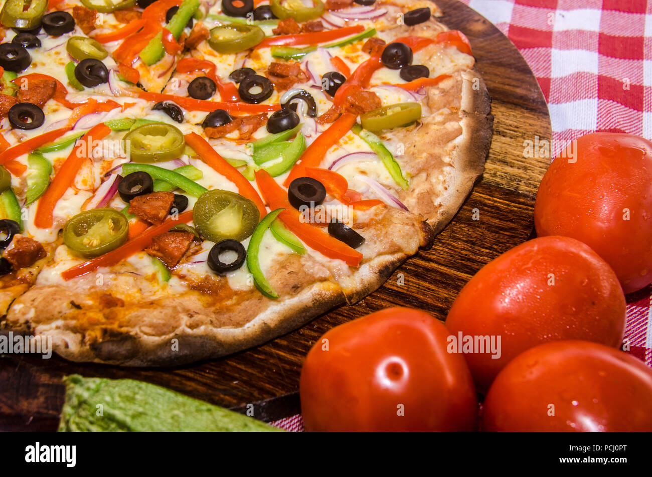 Pizza artigianale su una lastra di legno Foto Stock