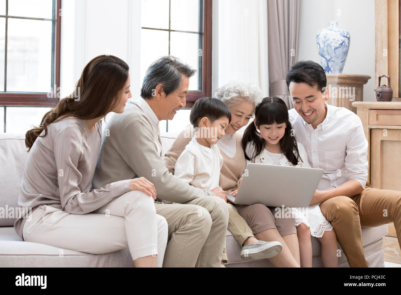 Felice famiglia cinese utilizzando computer portatile sul divano Foto Stock