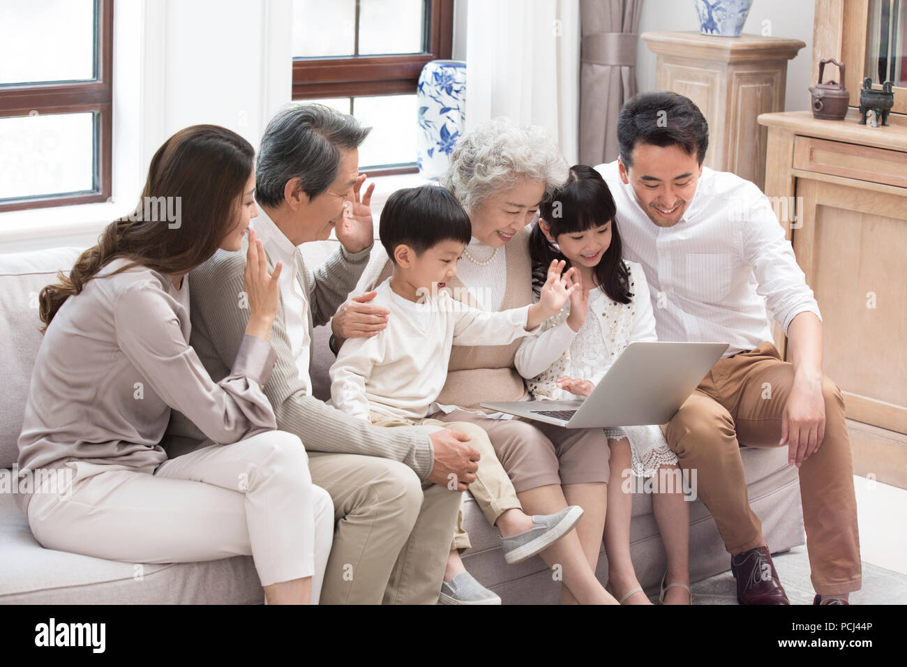 Felice famiglia cinese utilizzando laptop per le chat video Foto Stock