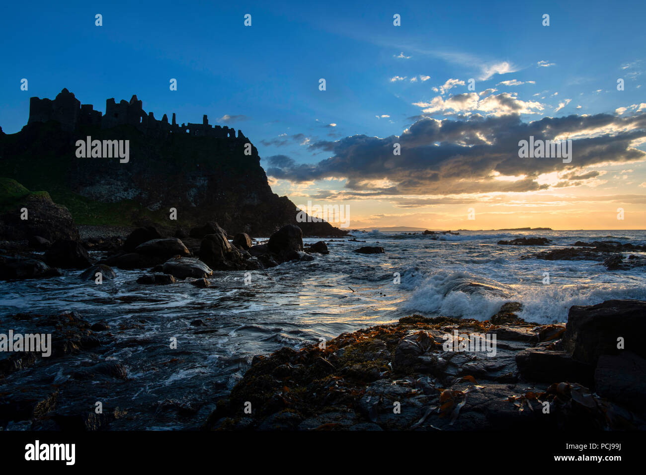 Rovine del Castello di Dunluce stagliano dal sunsetting sulla costa irlandese Foto Stock