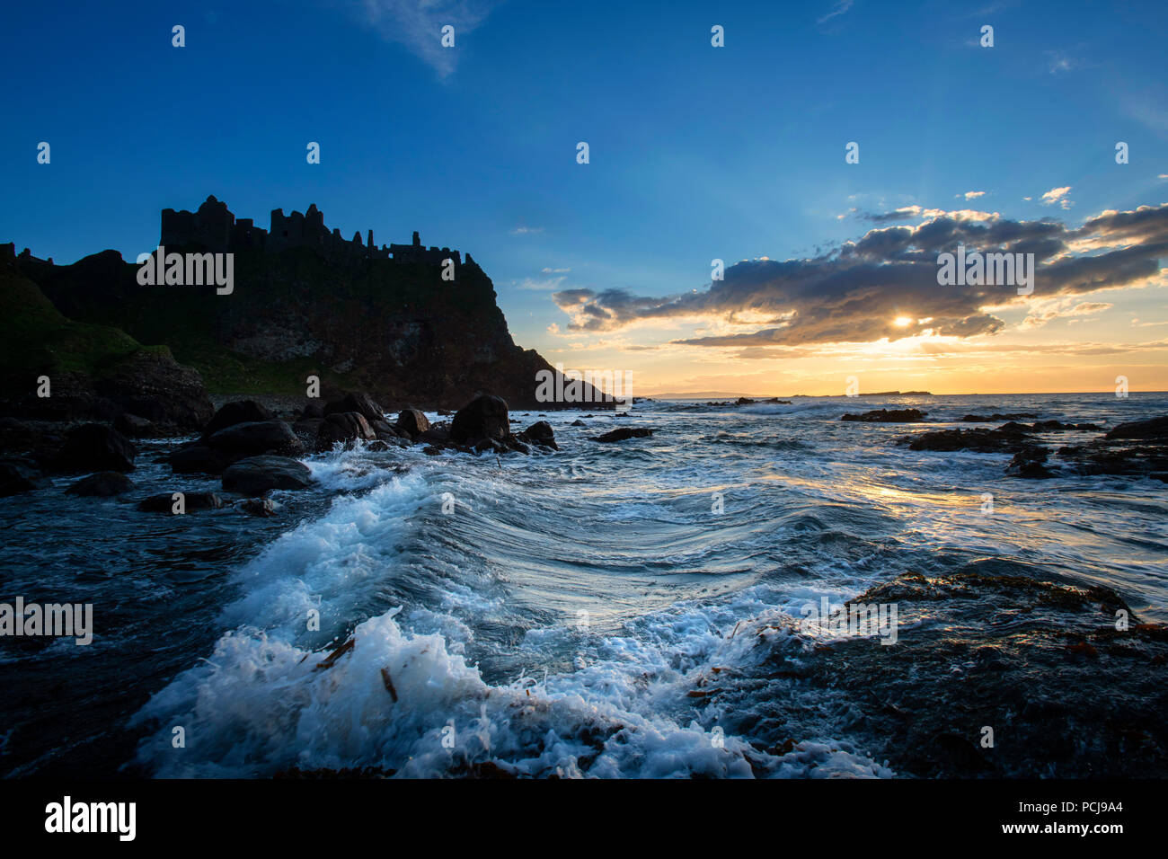 Rovine del Castello di Dunluce stagliano dal sunsetting sulla costa irlandese Foto Stock