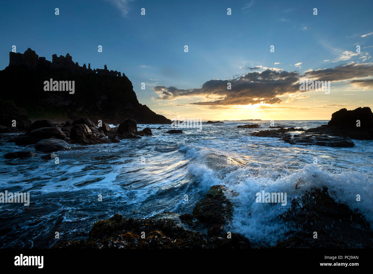 Rovine del Castello di Dunluce stagliano dal sunsetting sulla costa irlandese Foto Stock