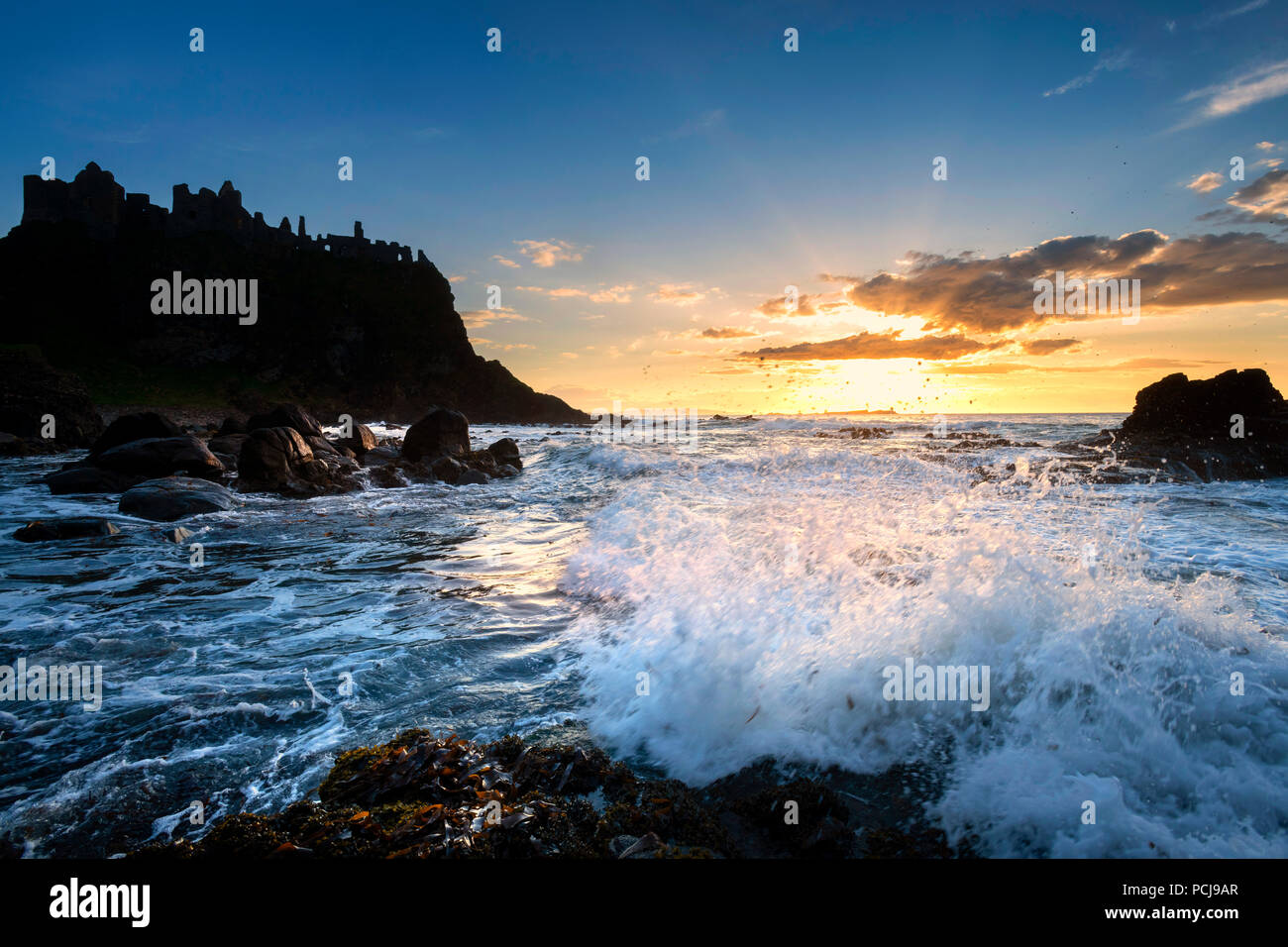 Rovine del Castello di Dunluce stagliano dal sunsetting sulla costa irlandese Foto Stock