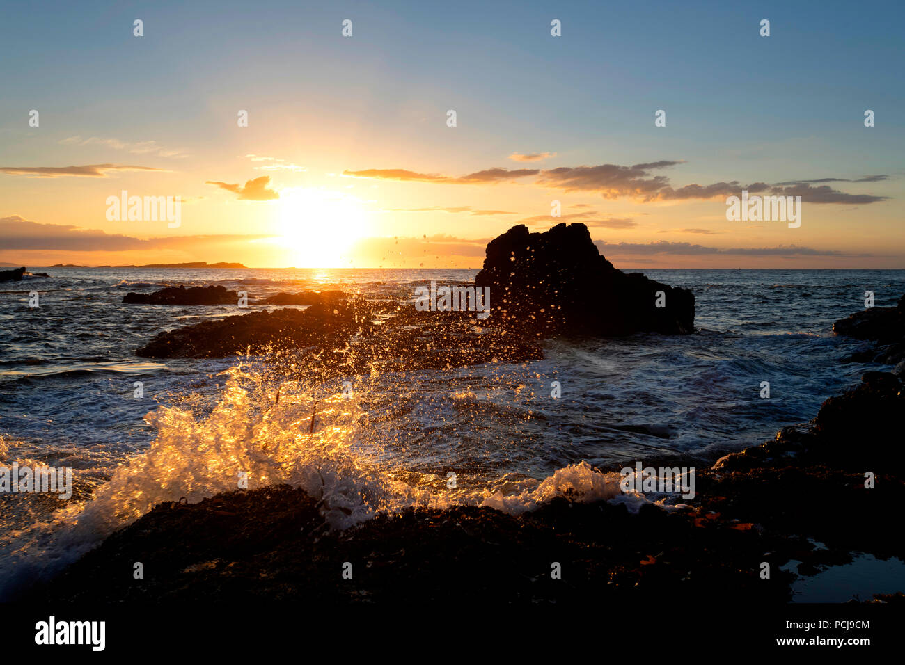 La luce dal sole che illumina le onde del mare a Dunluce Foto Stock