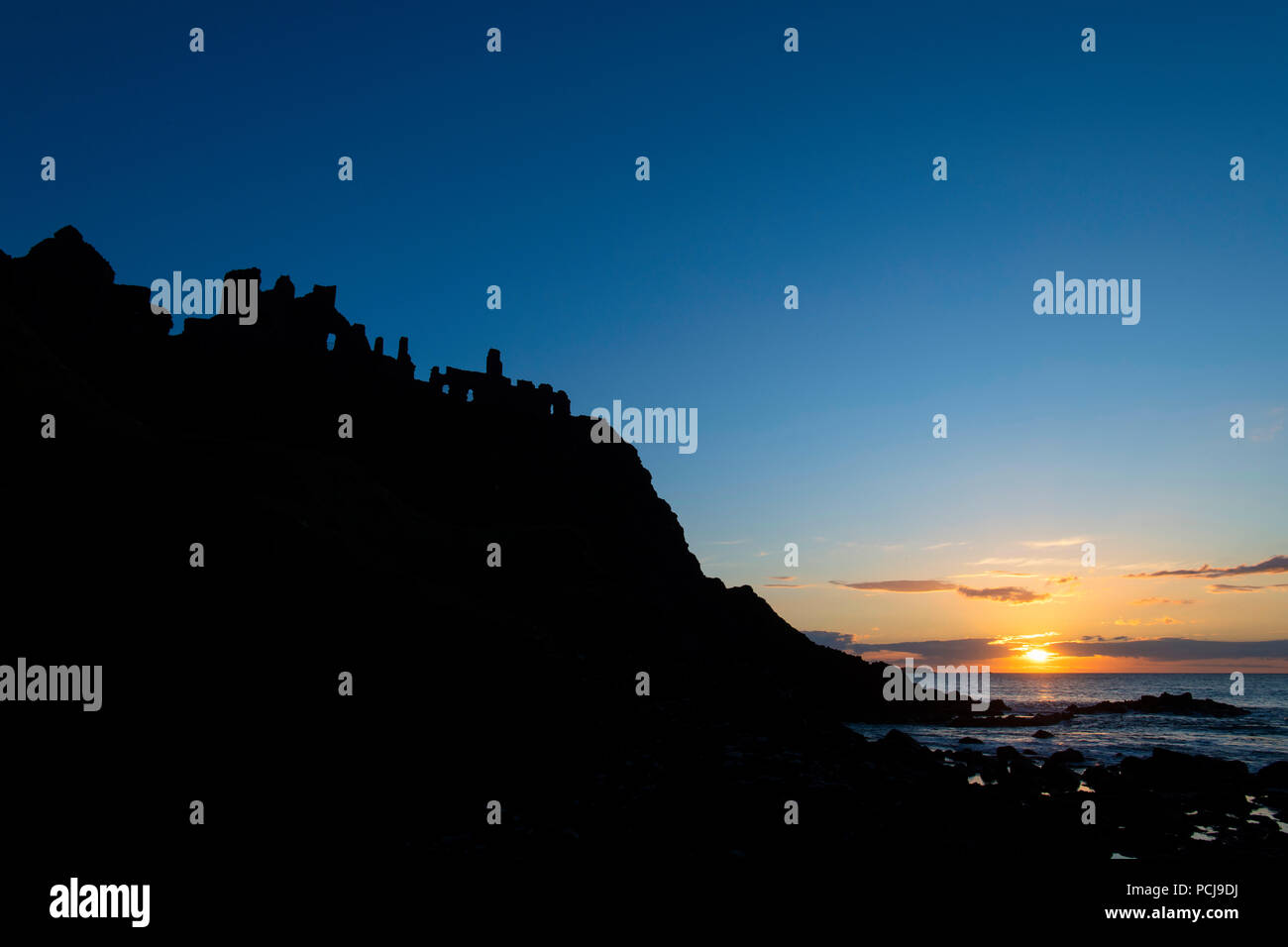 Rovine del Castello di Dunluce stagliano dal sunsetting sulla costa irlandese Foto Stock