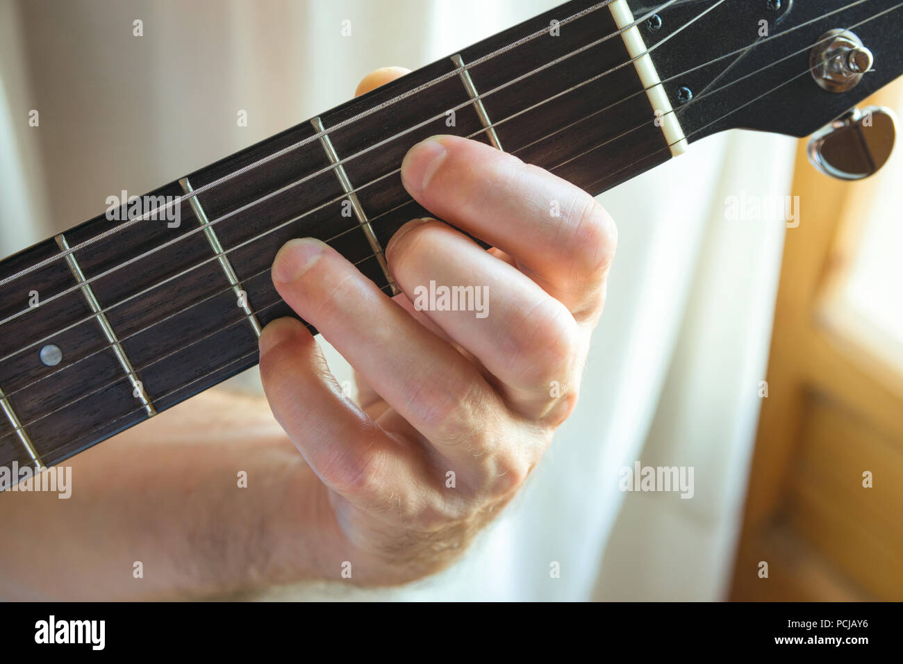 Giovane chitarrista holding fret board di suonare la chitarra corda dalla finestra. La musica che compongono la creatività dei talenti il concetto di prestazioni. Autentica vita candidi Foto Stock