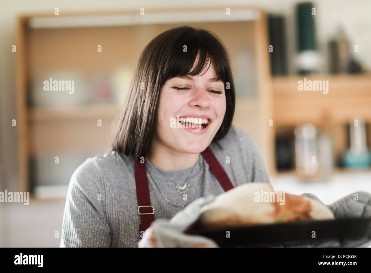 Donna sorridente in piedi in cucina tenendo un pane appena sfornato pagnotta di pane Foto Stock