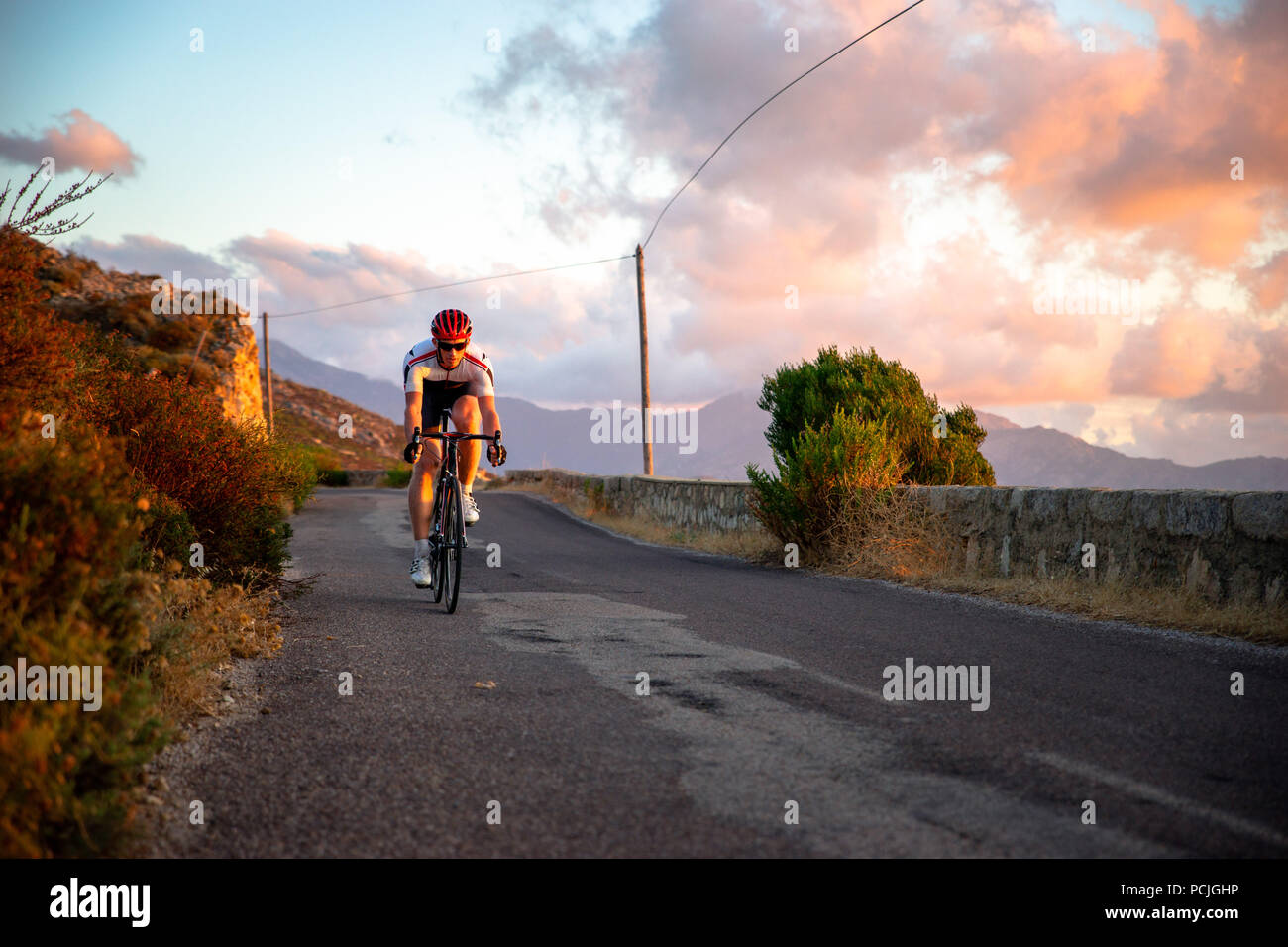L'uomo ciclismo su strada di montagna al tramonto, Corsica, Francia Foto Stock