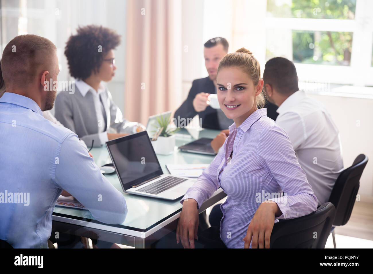 Ritratto di un felice giovane imprenditrice seduta in ufficio Foto Stock