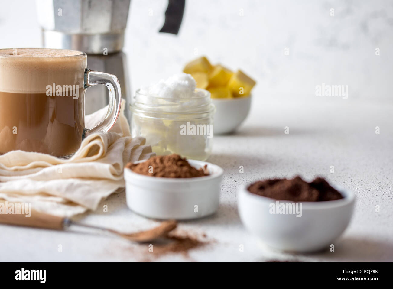 KETOGENIC dieta cheto bere. Caffè e cacao miscelata con olio di noce di cocco. Tazza di caffè antiproiettile con cacao e gli ingredienti su sfondo bianco Foto Stock