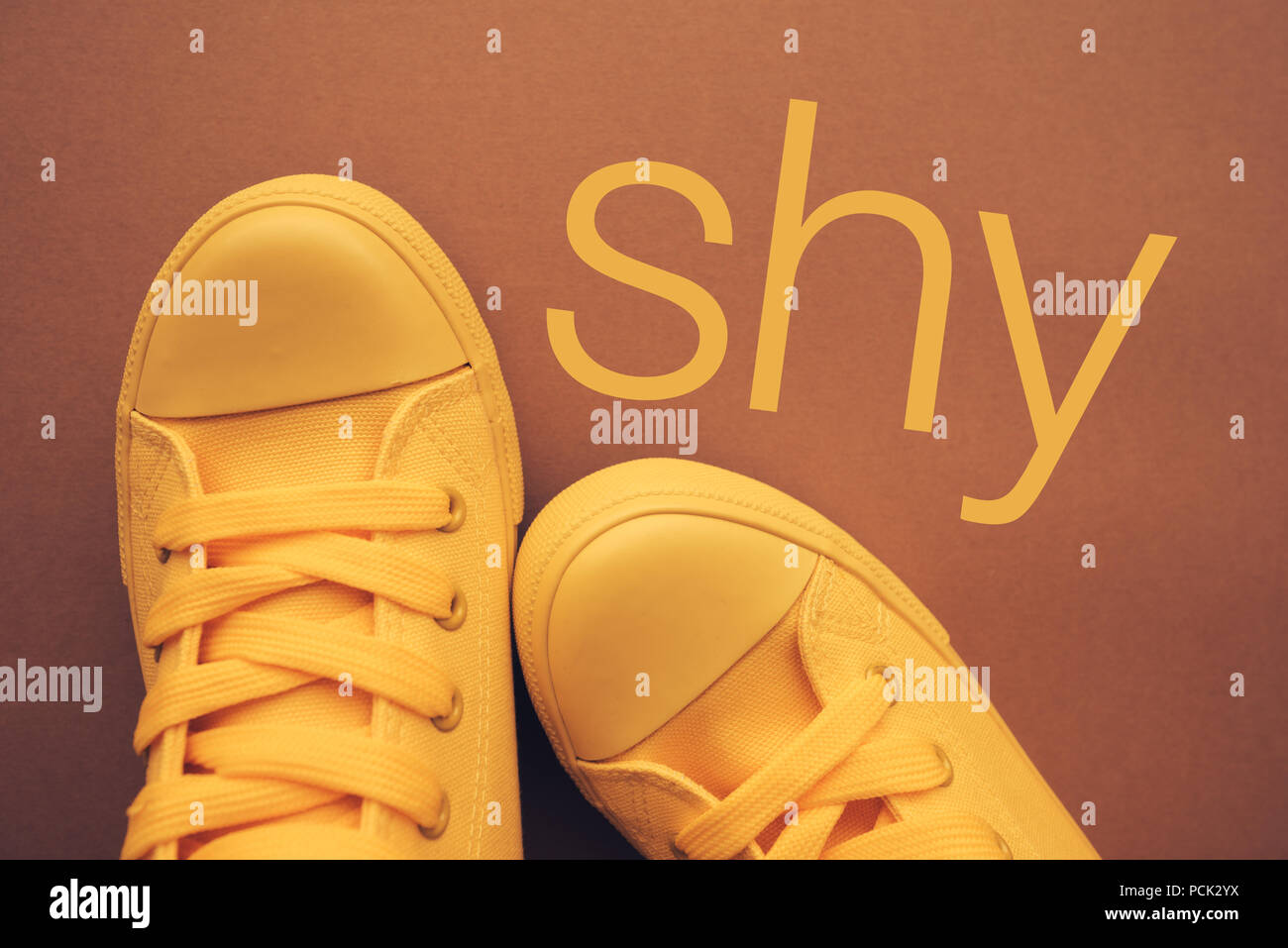 Persona timida e timidezza, immagine concettuale con giallo sneakers dal di sopra Foto Stock