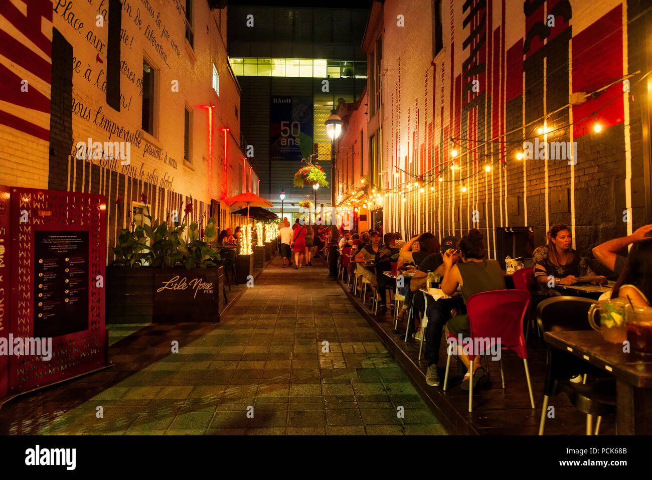 La gente seduta a bere sulla terrazza del pub L'Ile Noire di sera a Montreal - sul posto Paul-Emile Borduas, una strada laterale in prossimita di Rue St Denis. Foto Stock