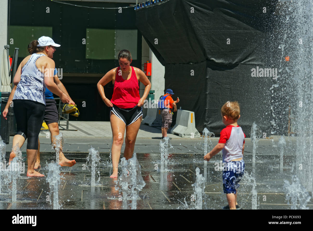 Persone mantenendo raffreddare in acqua delle fontane a Montreal nel 2018 canicola Foto Stock