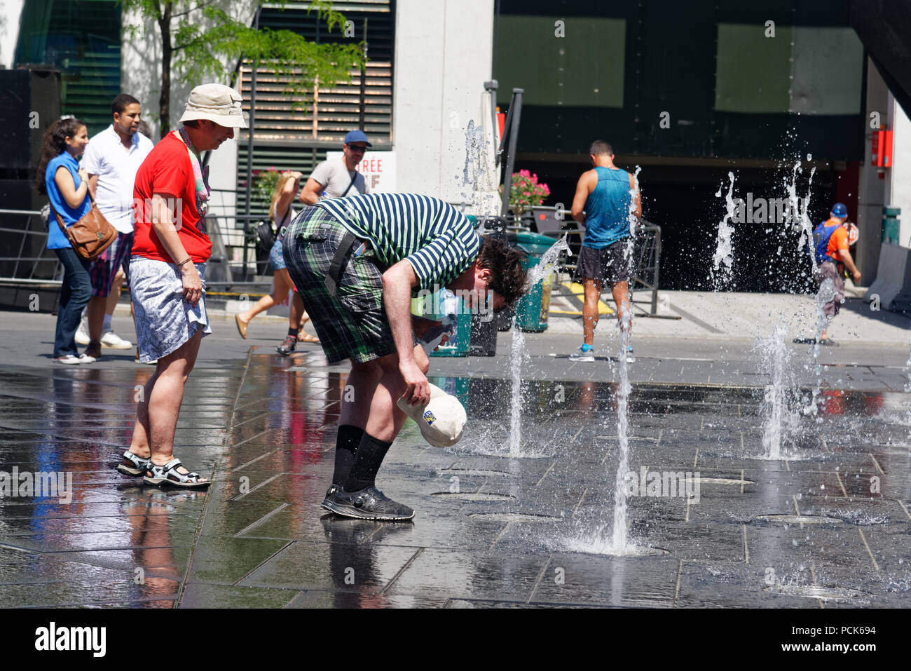 Un uomo bagnando la sua testa in acqua le fontane sulla Rue Jeanne previsti in Montreal durante il 2018 ondata di caldo. Foto Stock