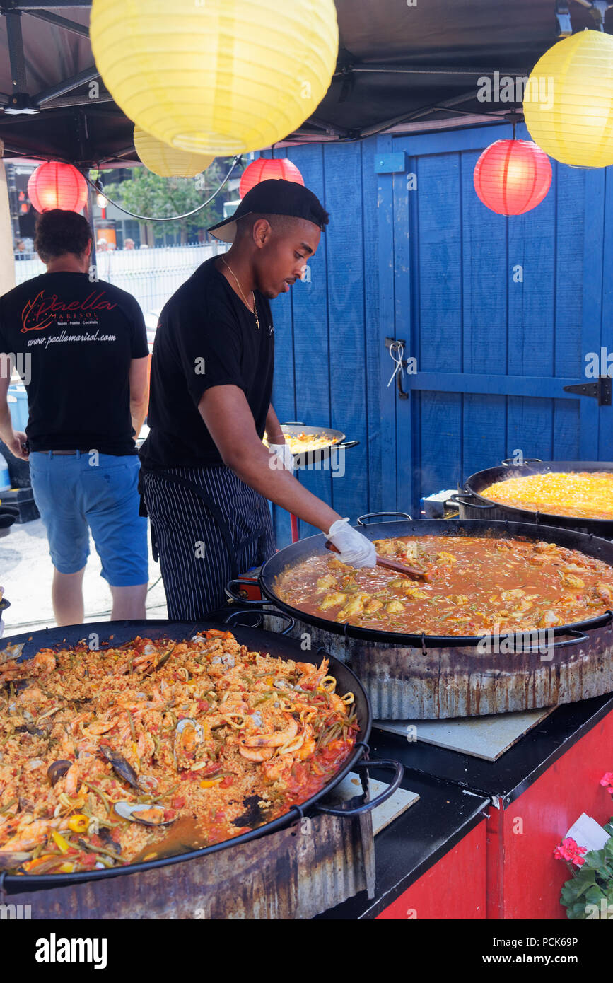 Un giovane uomo di preparare un enorme piatto di paella in un outdoor street food kiosk presso Bouffons Montreal Foto Stock