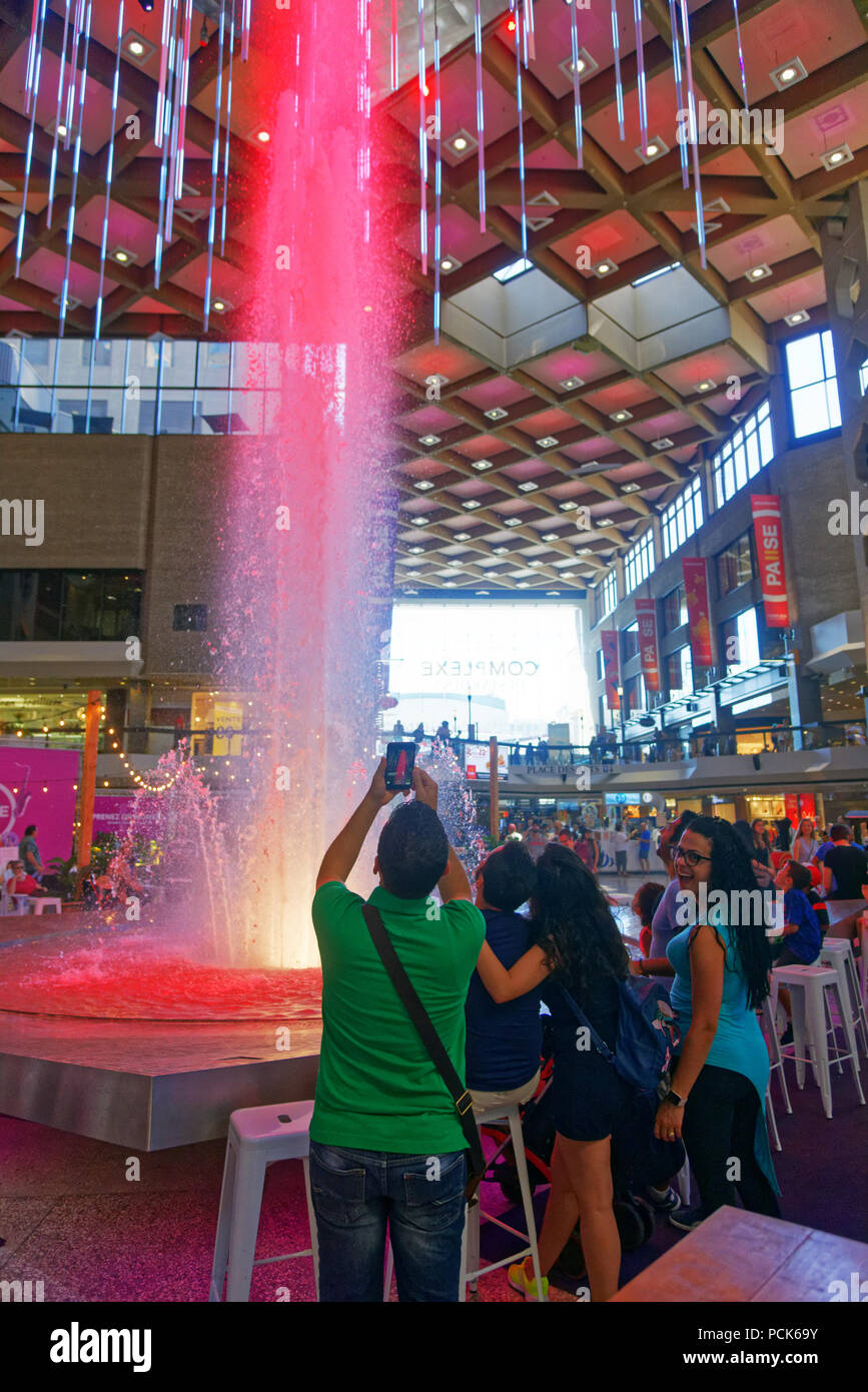 Un gruppo di giovani di scattare le foto di una grande fontana in Complexe Desjardins centro dello shopping nel centro cittadino di Montreal Foto Stock