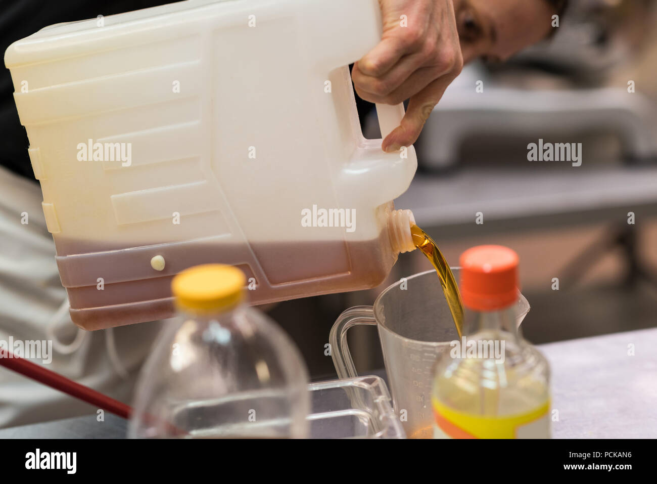 Lo Chef versando olio commestibile in un contenitore Foto Stock