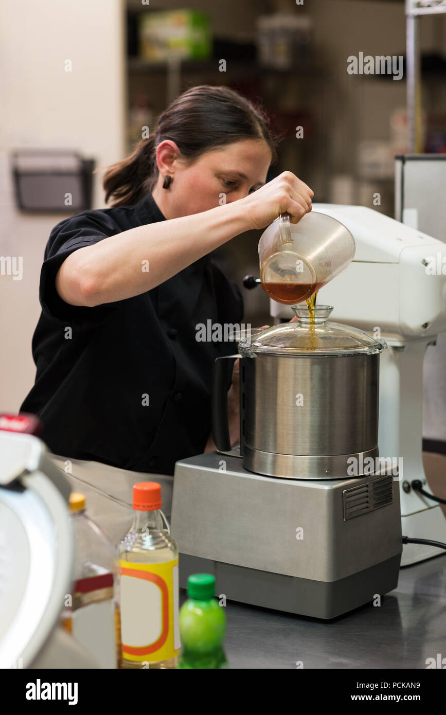 Lo Chef versando olio commestibile in una smerigliatrice Foto Stock