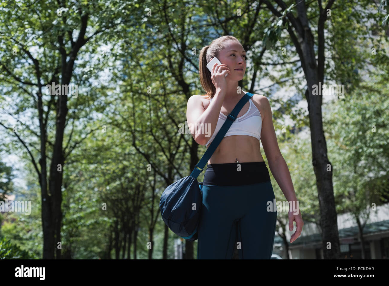 Sportivo da donna parlando al telefono mobile su strada Foto Stock