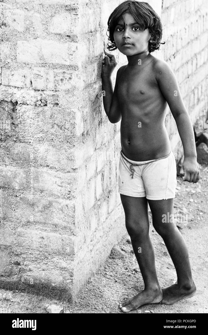 Pondicherry, PUDUCHERRY, Tamil Nadu, India - Marzo circa, 2018. Unidentified piccolo indiano ragazzo a piedi nudi in usurati poveri vestiti giocando con il muro mi Foto Stock