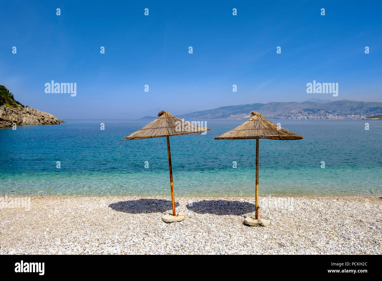 Reed-coperto ombrelloni sulla spiaggia di ghiaia, Manastiri beach, Plazhi i Manastirit, vicino Saranda, Sarandë, Mar Ionio, Qark Valona Foto Stock