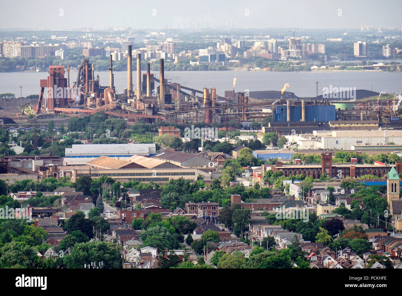Hamiilton zone residenziali in primo piano, le frese in acciaio in settori industriali lungo waterfront skyline con autostrada QEW o Queen Elizabeth titolo sopra il lago Foto Stock