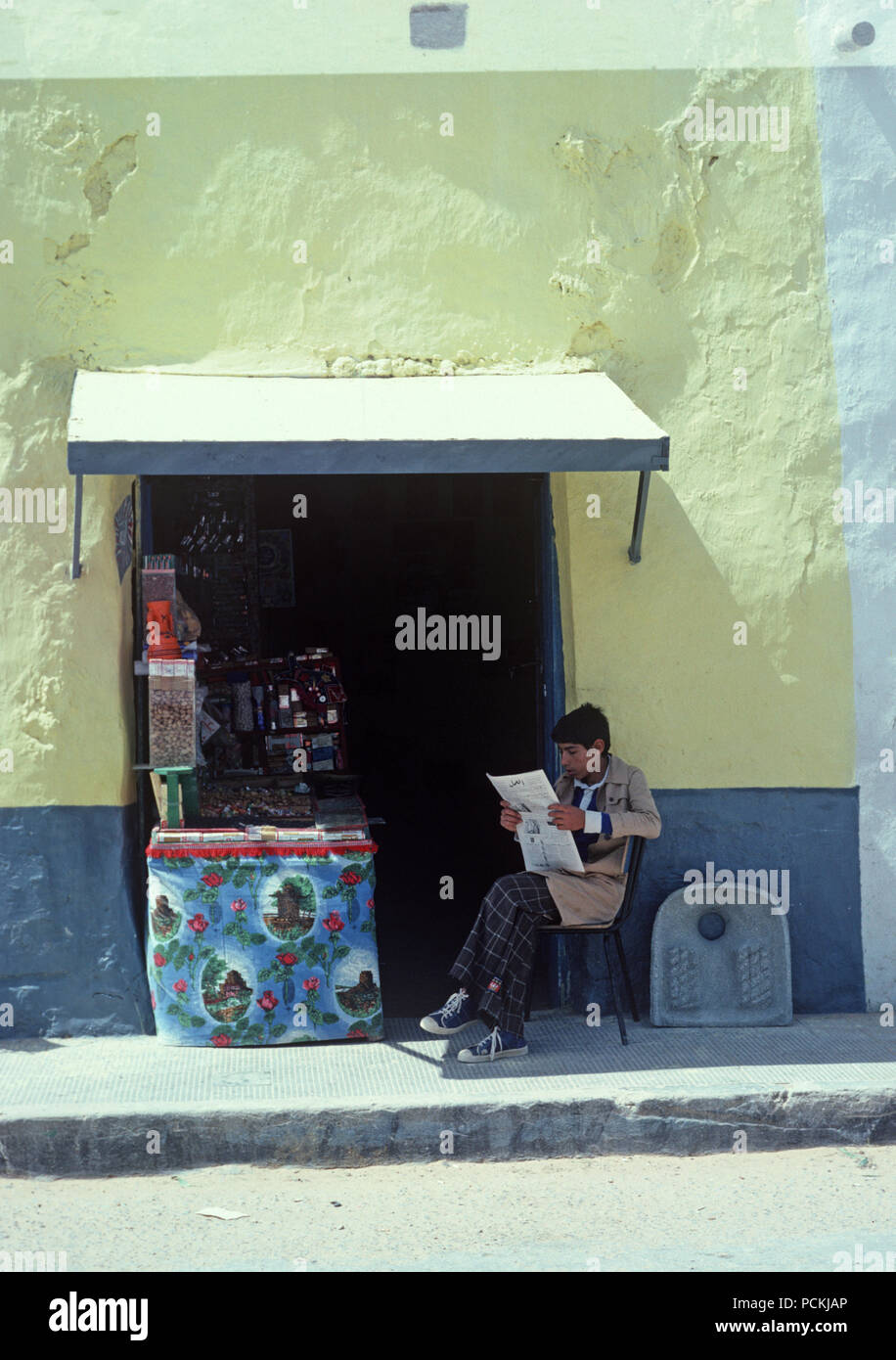 Arab Berger quotidiano di lettura al di fuori del tabaccaio e negozio di dolci a sud della Tunisia, Nord Africa Foto Stock