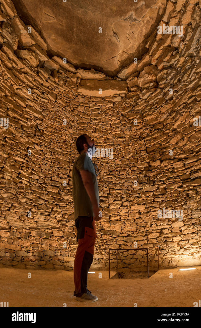 Il visitatore a Tholos de El Romeral camera principale. Egli sta osservando il capstone megalitica. Antequera, Malaga, Spagna Foto Stock