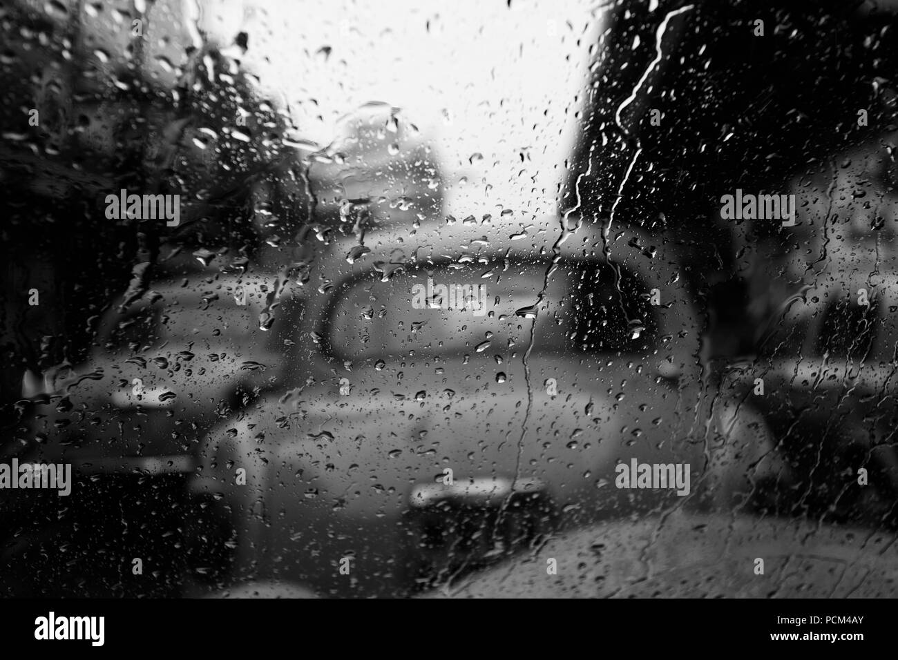 Gocce di pioggia sul vetro in focus & al di fuori della cabina di messa a fuoco in bianco e nero di Calcutta, in India. Foto Stock