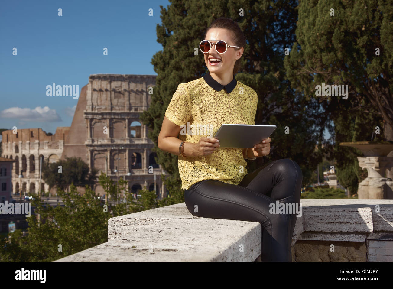 Sorridente donna elegante in giallo camicetta con tablet PC non lontano dal Colosseo Foto Stock