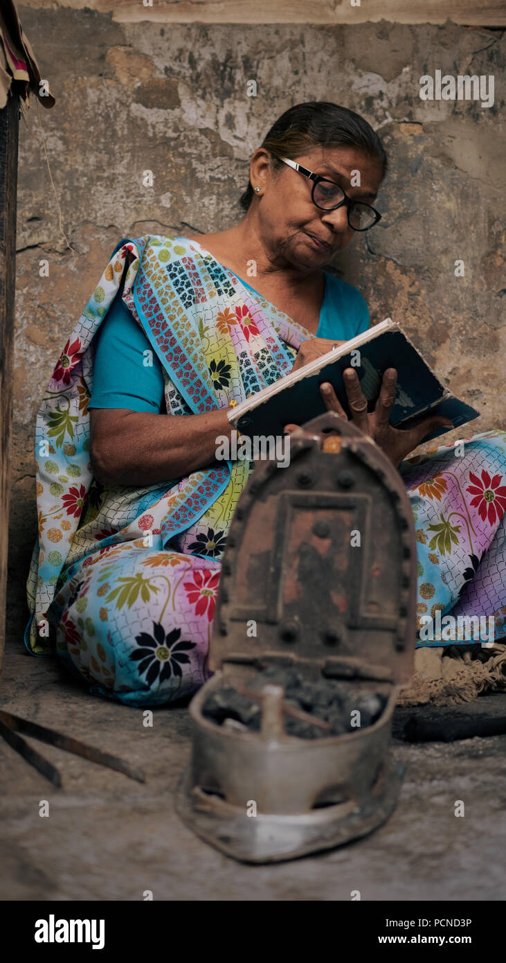 Una donna controlla i suoi conti prima di iniziare il suo lavoro come un servizio stireria lady Foto Stock