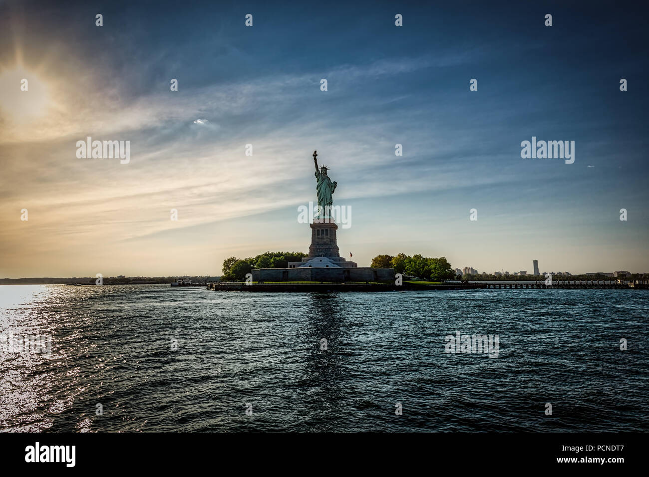 La Statua della Libertà di New York con il sole che tramonta dietro di lei. Foto Stock