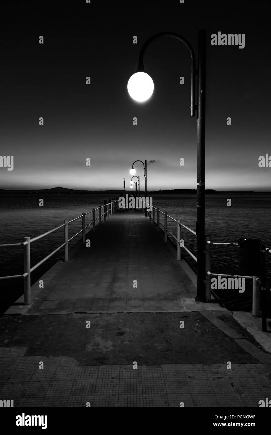 Alcune persone su un molo presso il lago Trasimeno (Umbria, Italia) al tramonto Foto Stock