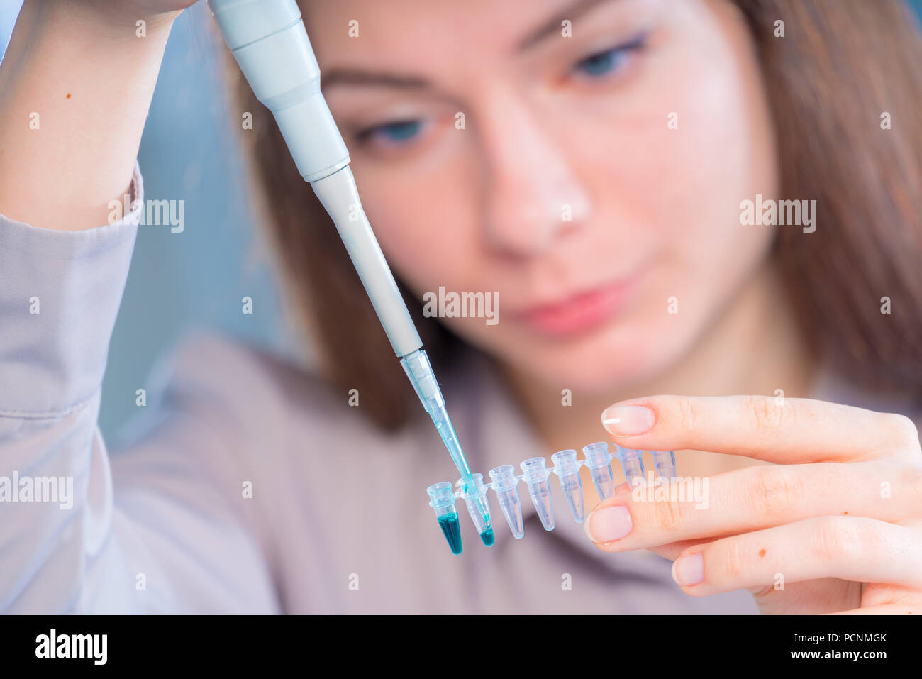 Tecnico di femmina con pipetta in lad per analisi forense del DNA testing Foto Stock