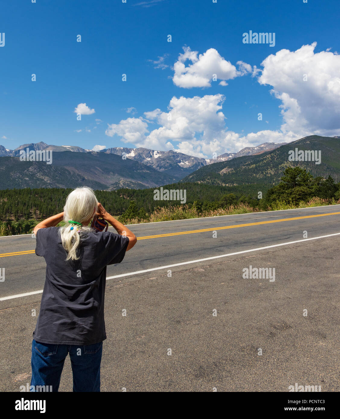 ESTES PARK, CO, Stati Uniti d'America-17 luglio 18: Un grey-haired femmina con torna alla fotocamera, prendendo un immagine di telecamera di picchi di montagna in montagna rocciosa N.P. Foto Stock
