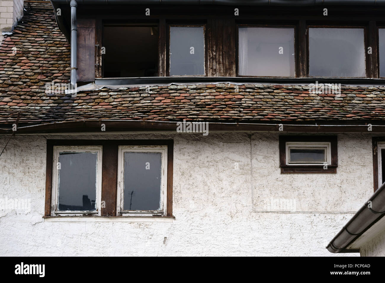 Pendente, fatiscente e nostalgico windows e tegole di un vecchio e un edificio elencato. Foto Stock