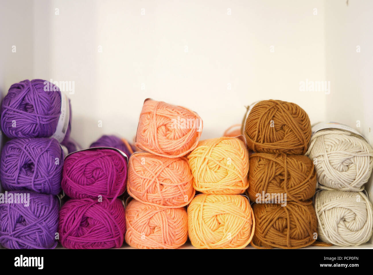 Una pila di palline di lana in colori diversi Foto Stock