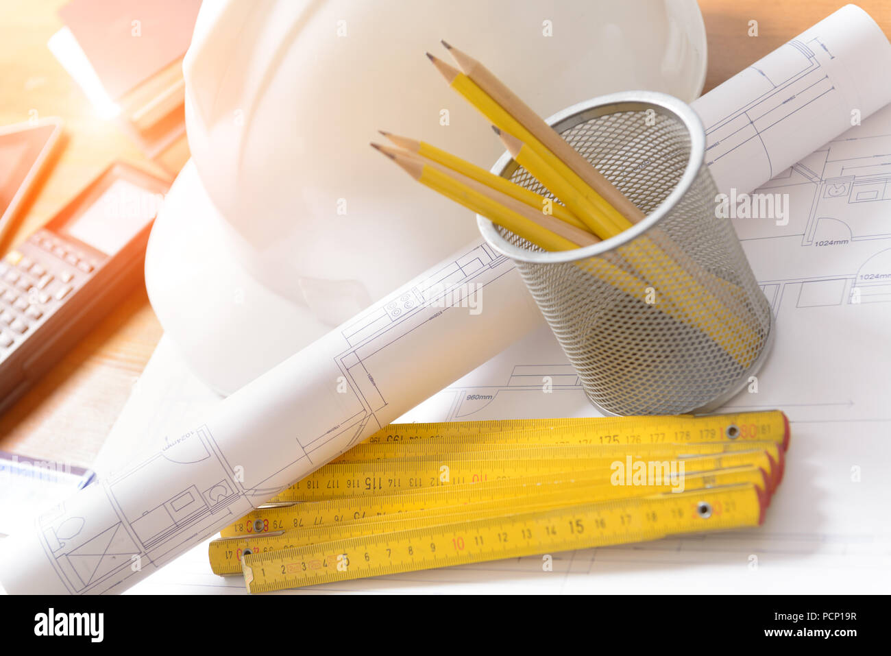 Piani di costruzione con il casco e gli strumenti di disegno su blueprint con la calcolatrice in uno sfondo Foto Stock