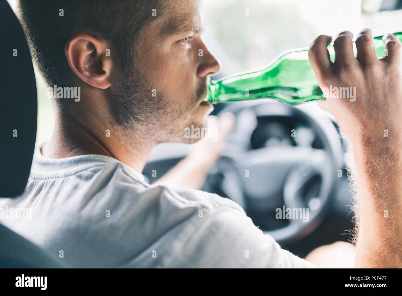 Autista ubriaco bere dietro al volante di una vettura Foto Stock