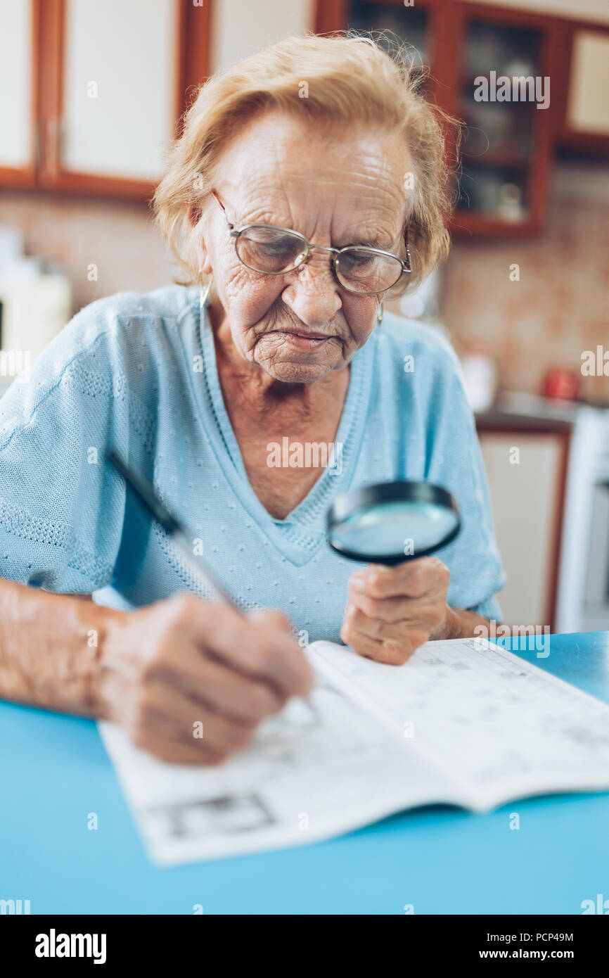 Senior donna nella sua 80s gode di risolvere un cruciverba Foto Stock