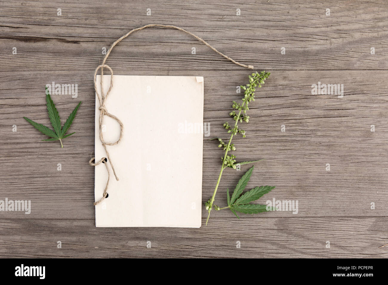 La canapa foglie e fiori con artigianali fatti a mano notebook sul vecchio grunge sfondo di legno. Vista dall'alto. In stile minimalista mockup. Foto Stock
