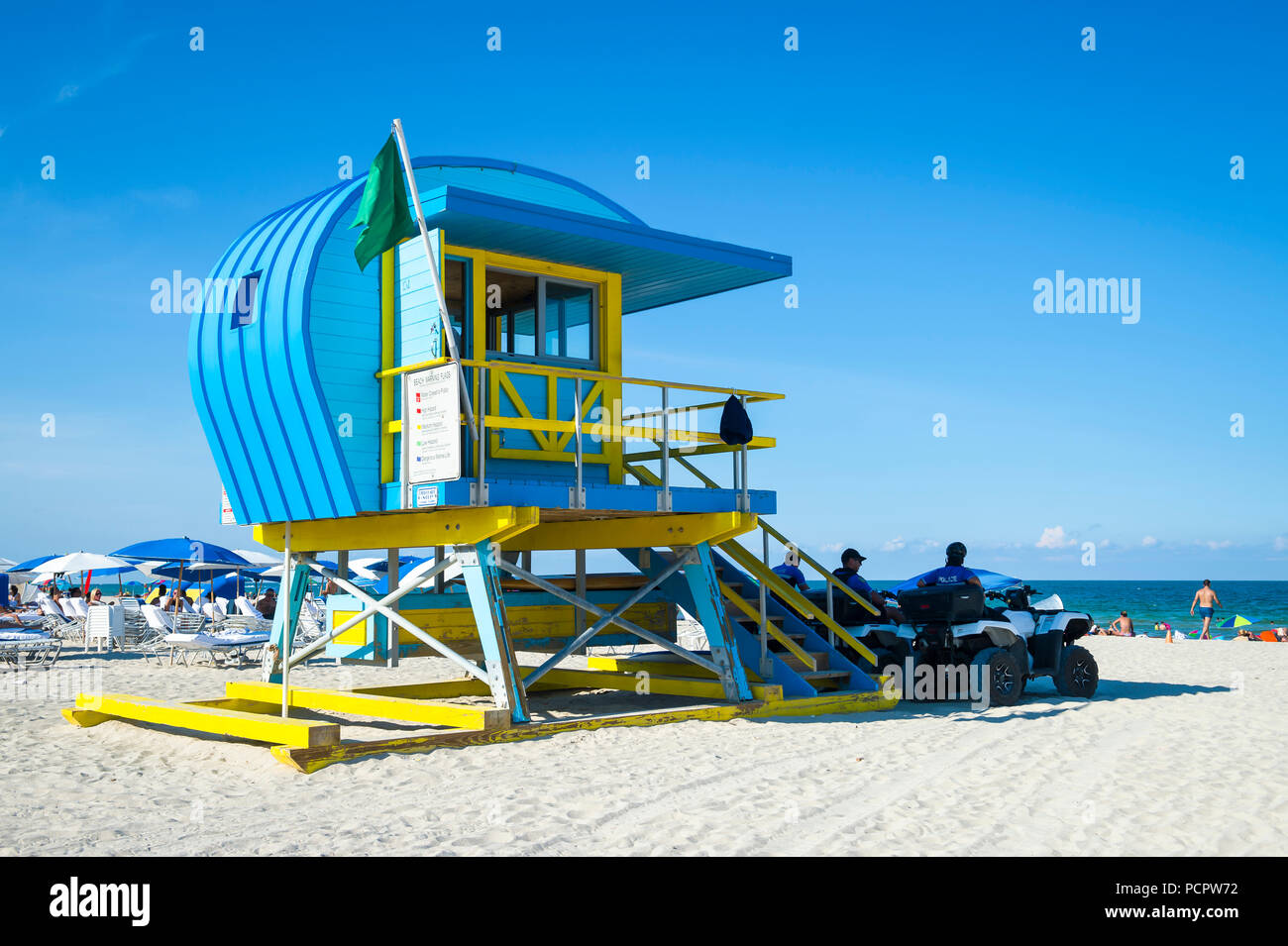 Vista panoramica di un iconico giallo e blu torre bagnino e ombrelloni sulla spiaggia di South Beach a Miami Foto Stock