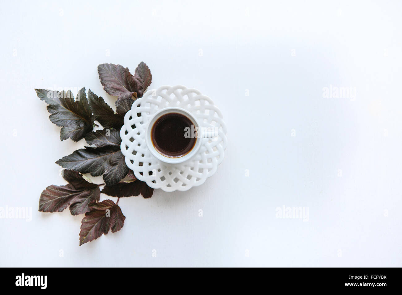 Una tazza di caffè aromatico o tè nero. Nelle vicinanze si trovano le foglie di autunno. Semplice minimalista design d'autunno. Foto Stock