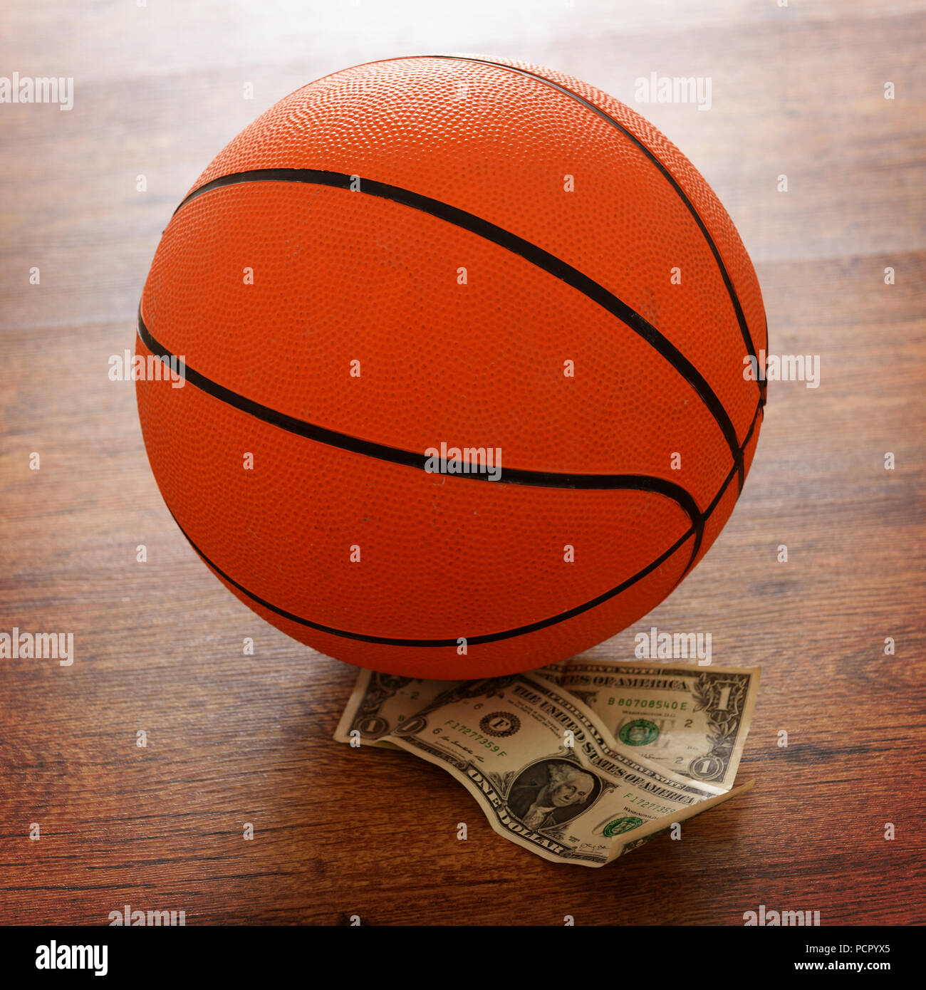 Basketball bet foto concettuale con il denaro e la sfera su un pavimento di legno Foto Stock