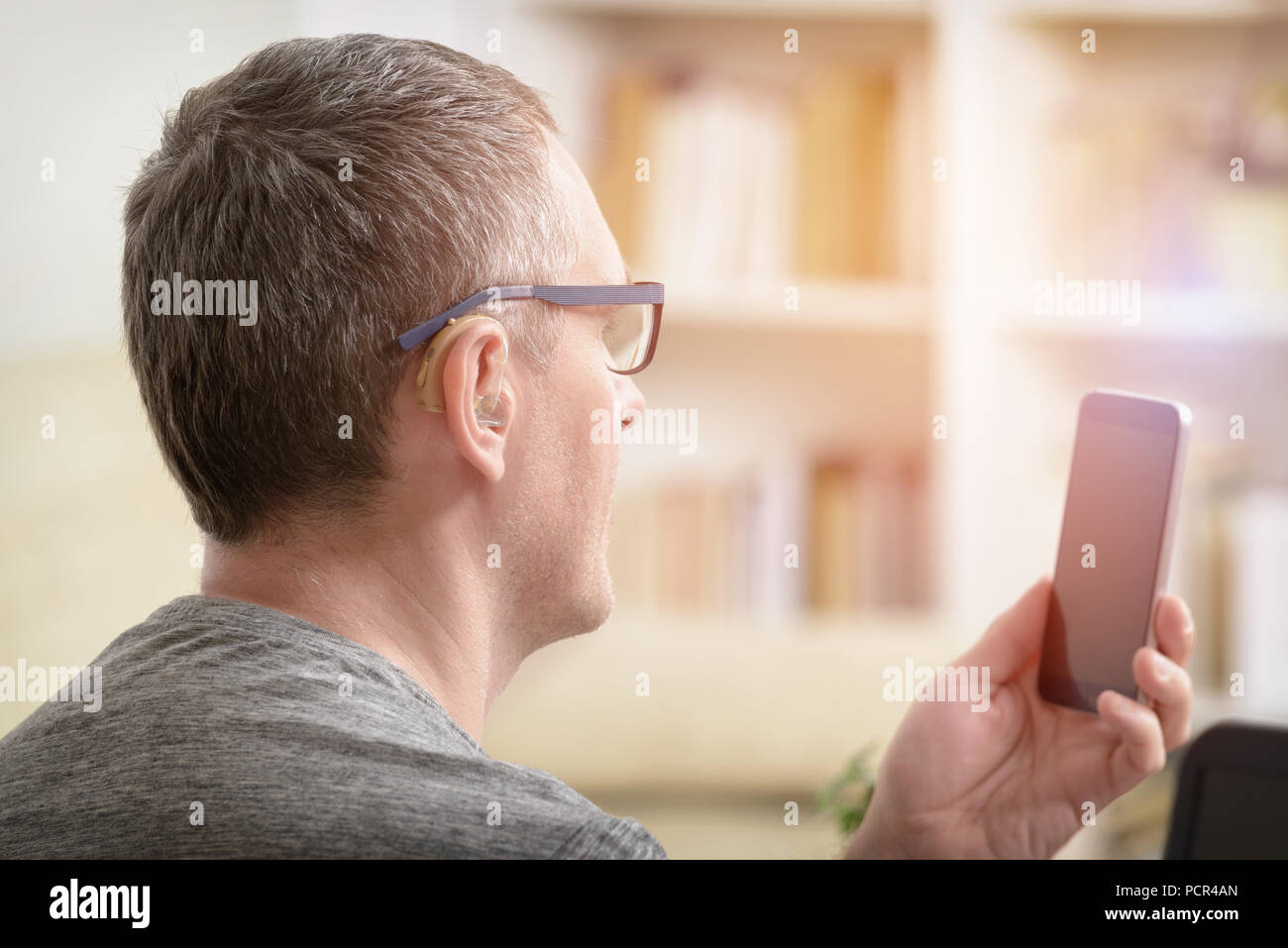 Non udenti uomo al lavoro con il computer portatile e il telefono cellulare a casa o in ufficio Foto Stock