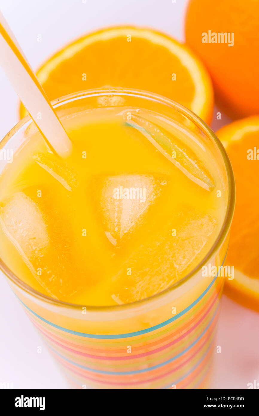 Arance, ghiaccio e succo di frutta in vetro su bianco Foto Stock
